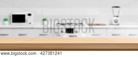 Wooden Counter Top On Kitchen Blur Background With Microwave Oven, Gas Stove, Blender And Cutting Bo