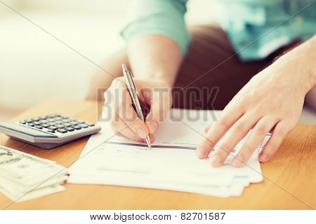 savings, finances, economy and home concept - close up of man with calculator counting money and making notes at home