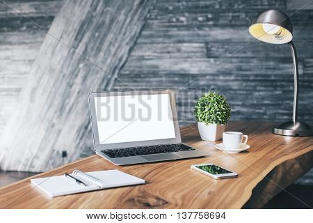 Wooden designer desktop with blank white laptop stationery items coffee cup cell phone plant and table lamp. Mock up