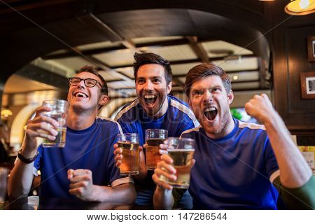 sport, people, leisure, friendship and entertainment concept - happy football fans or male friends drinking beer and celebrating victory at bar or pub