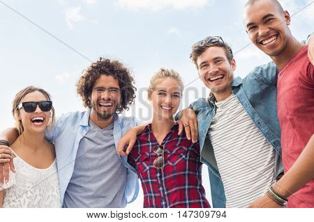 Portrait of group of happy friends embracing and looking at camera. Happy young men and women having fun together. Young cheerful guys and girls enjoying each other company.