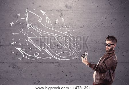 A hipster guy opening his point of view through looking a vintage camera concept with illustratied drawn arrows on urban wall