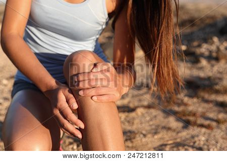 Medical health sport injury runner woman with hurting knee. Sports fitness athlete touching knees with pain.