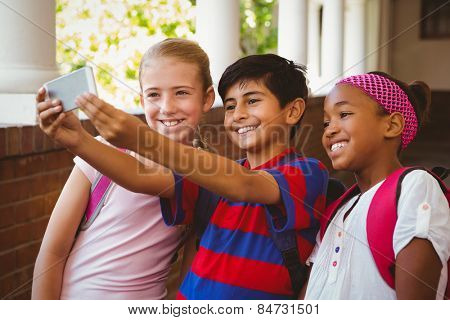 Portrait of happy little school kids taking selfie in school corridor