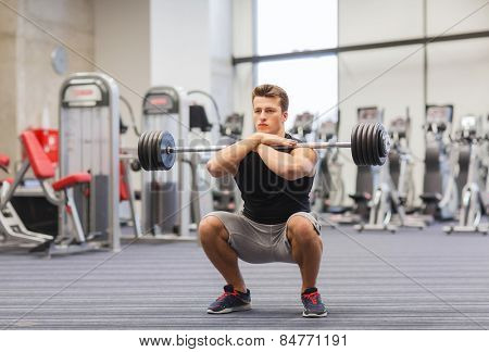 sport, bodybuilding, lifestyle and people concept - young man with barbell doing squats in gym