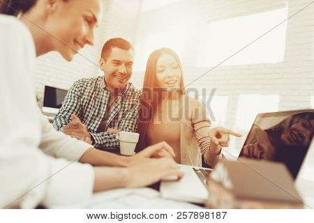 Young Man And Woman With Smiling Realtor In Office. Blueprint On Wooden Desk. Real Estate Concepts. 