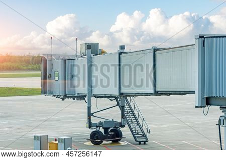 Empty Aircraft Parking Passenger Air Bridge At Airport Apron Against The Backdrop Of A Beautiful Sky