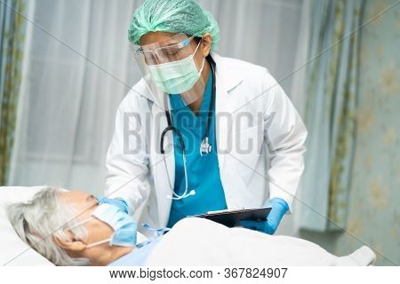 Asian Doctor Wearing Face Shield And Ppe Suit To Check Senior Woman Patient Protect Safety Infection