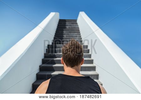 Fitness man looking ahead at stairs climbing challenge. Runner going up running staircase for cardio goal doing weight loss choice in healthy lifestyle. Man choosing difficult path.