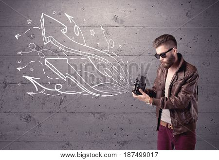 A hipster guy opening his point of view through looking a vintage camera concept with illustratied drawn arrows on urban wall