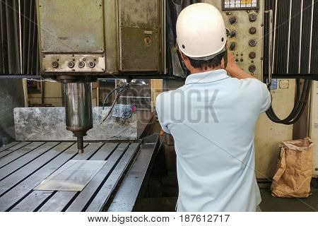 The CNC machine operator operate the old double column CNC machine with safety hat. CNC machine operation concept