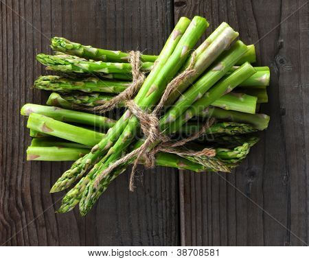 Bunches of asparagus tied with twine on a wood background. Overhead view in horizontal format.