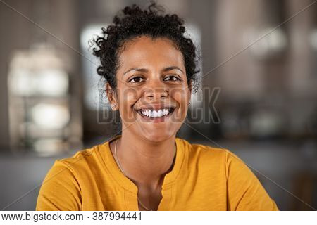 Portrait of a beautiful mid adult woman smiling at home. Middle aged african woman in casual looking at camera with copy space. Cheerful mixed race girl relaxing at home with big laugh.