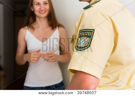 Police officer at front door of home interrogating a woman or witness regarding a police investigation