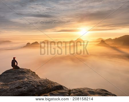 Tourist Sit On Peak Of Sandstone Rock And Watching Into Colorful Mist And Fog In  Morning Valley. Sa