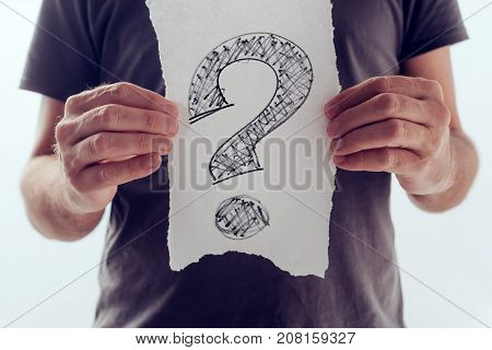 Question mark looking for answers. Man holding paper with scribbled interrogation point query or eroteme punctuation