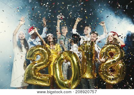 Office christmas party. Group of joyful colleagues having fun at new year celebration. Happy smiling people holding golden number balloons, 2018 year symbol. Greeting card for co-workers mockup