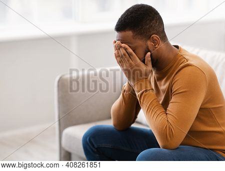 Male Depression. Desperate Depressed African Man Covering Face Crying Having Problems Sitting On Cou