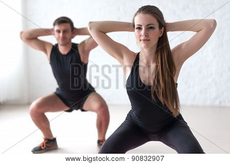 Fitness man and woman exercising squat exercise hands behind head concept sport, training, warming u