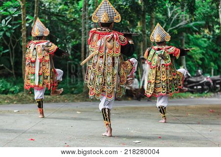 Three Men In Traditional Costumes Perform A Balinese War Dance Called Tari Baris Gede Outdoors. Danc