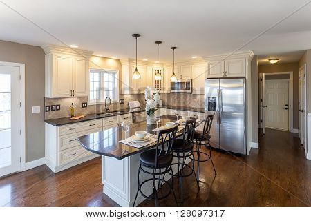 Beautiful staged kitchen room in a modern house with granite countertops and antique finished cabinets.