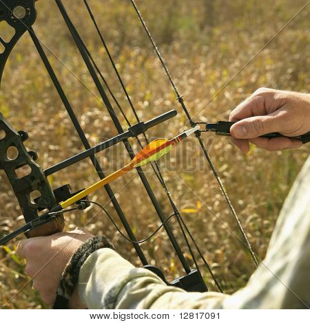 Bow hunter händer som håller compoundbåge i fältet.