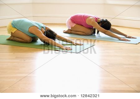 Twee jonge vrouwen op matten van de yoga doen van kind pose.