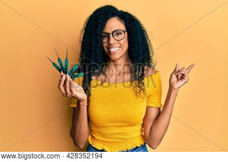 Middle age african american woman holding picklock to unlock security door smiling happy pointing with hand and finger to the side 