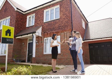 Young Family Collecting Keys To New Home From Realtor