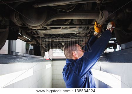 Suspension system of SUV restoration in garage. Mechanic recovering car wheel under vehicle