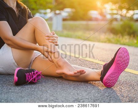 Running Injury Leg Accident- Sport Woman Runner Hurting Holding Painful Sprained Ankle In Pain. Fema