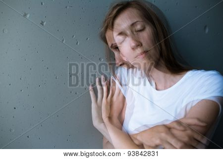 Young woman suffering from a severe depression/anxiety (color toned image; double exposure technique is used to convey the mood of unease, progression of the anxiety/depression)