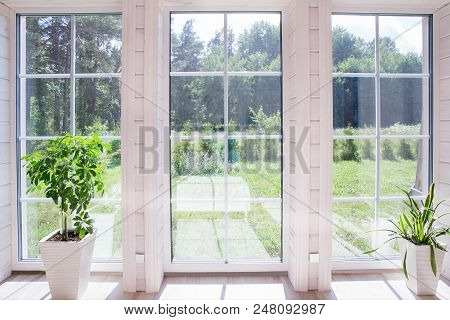 Bright Interior Of The Room In A Wooden House With A Large Window Overlooking The Summer Courtyard. 