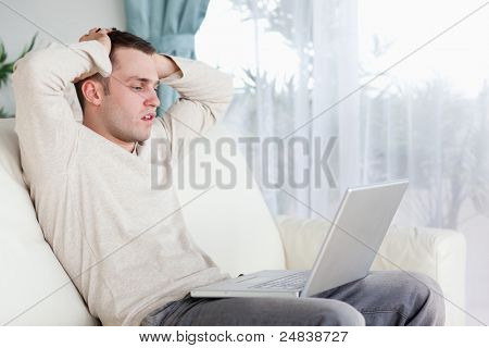 Sad man working with his notebook in his living room