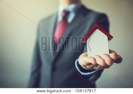 Business Man In Suit Having Miniature House On Palm Of His Hand - Business Mortgage, Property Loan,