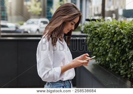 Happy Pretty Brunette Girl Using Mobile Phone Near Office, Beautiful Woman Browsing Phone And Doing 