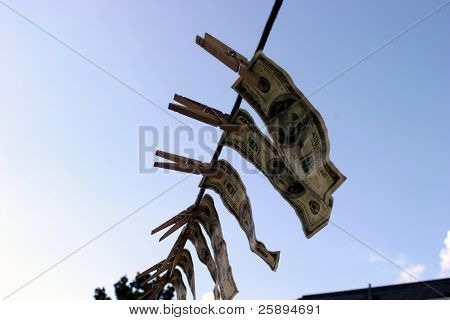 Hundred dollar bills hanging on a rope.
 Money laundering concept 
