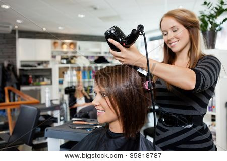 Brushing esthéticienne les cheveux après avoir donné une nouvelle coupe de cheveux au salon