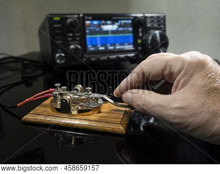 Selective Focus Of Mans Hand On A Telegraph Key With Radio Defocused In Background