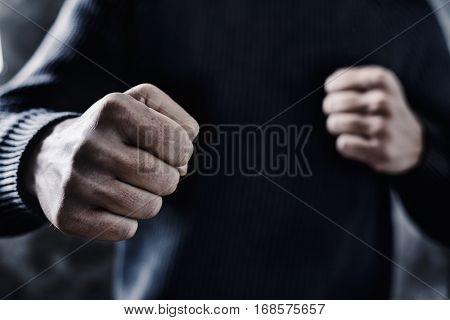 closeup of a young caucasian man in casual wear with a threatening gesture, ready to punch or fight with his fists