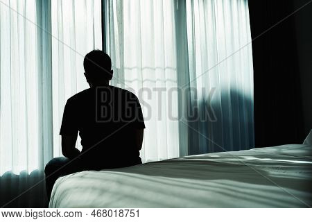 Silhouette Depressed Man Sadly Sitting On The Bed In The Bedroom. Sad Asian Man Suffering Depression