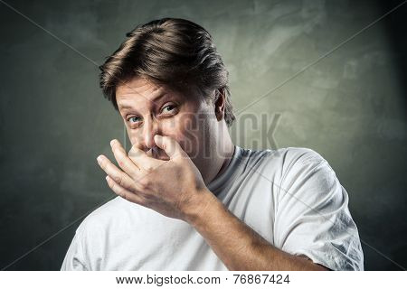 Man with disgusted expression closing his nostrils