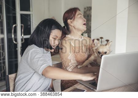 Asian Grandmother And Kid Using Laptop Together. Thai Elderly Woman And Child Talk On Video Call And