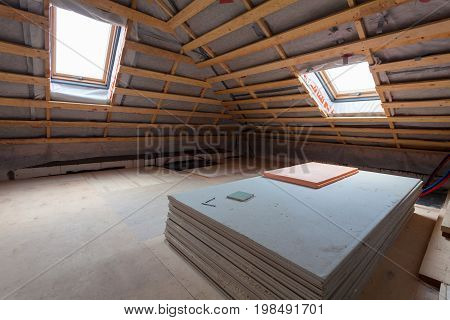 Interior of room apartment with new windows and materials (pieces of drywall) during on the renovation overhaul and construction ( remodeling and repairing wall from gypsum plasterboard or drywall and inside roof warming)