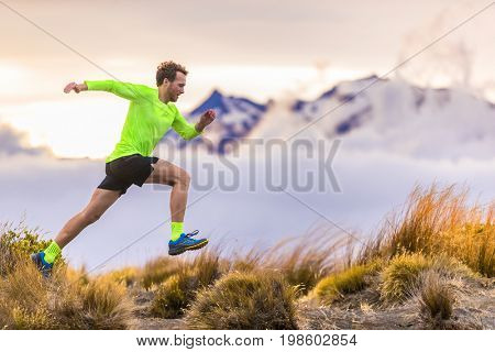 Trail runner man running on New Zealand mountains nature. Sport athlete jumping over hills with mountain trail at dusk landscape background . Active health and motivation lifestyle