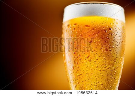 Beer. Cold Craft light Beer in a glass with water drops. Pint of Beer close up on amber color background. Border design