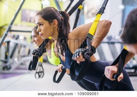 Women doing push ups training arms with trx fitness straps in the gym Concept workout healthy lifest