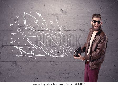 A hipster guy opening his point of view through looking a vintage camera concept with illustratied drawn arrows on urban wall