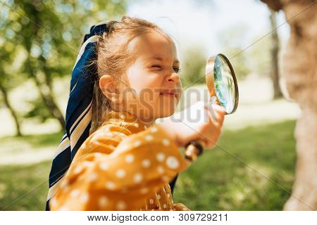 Curious Kid With Magnifying Glass Exploring The Nature Outdoor. Adorable Little Explorer Girl Playin