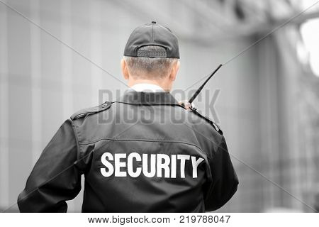 Male security guard using portable radio outdoors